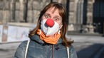 Karnevalistin in Köln mit Pappnase über der FFP2-Maske.