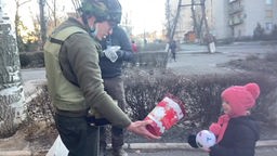 Soldat reicht kleinem Mädchen ein Geschenk 