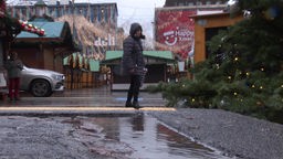 Eine Person steht auf dem Weihnachtsmarkt-Gelände. Die Buden haben wegen des Wetters geschlossen.