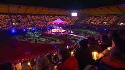 Tausende Menschen sitzen im Stadion und singen