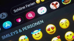 Der Spruch "Schöne Ferien", verbunden mit drei verschiedenen Emojis, ist auf einem Tablet zu sehen.
