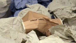 Ein Kaffeebecher mit herkömmlichen Papierhandtüchern im Müll