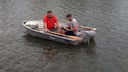 Zwei Männer sitzen in einem Boot, einer davon notiert sich etwas auf einem Klemmbrett.