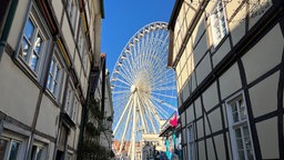 Blick durch eine Gasse mit Fachwerkhäusern auf ein Riesenrad