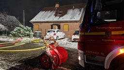 Haus mit verschneitem Dach. Davor ein Feuerwehrwagen 