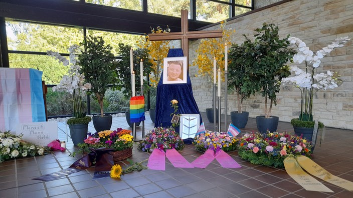 Ein Kreuz mit einem Foto von Malte sowie vielen Blumen. 