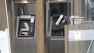 Man sieht zwei Geldautomaten in einer Volksbankfiliale. Der rechte Automat wurde gesprengt und ist stark beschädigt.