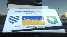 Ein Schild mit der Ukraineflagge liegt hinter der Windschutzscheibe