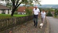 Ein Mann und eine Frau gehen mit einem Hund spazieren. 