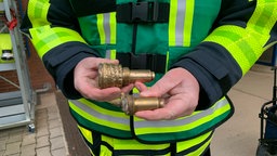 Ein Mitarbeiter hält Zünder der entshärften Bombe in der Hand