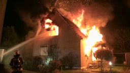 Ein Einfamilienhaus in Lübbecke steht in Flammen, die Feuerwehr löscht das Gebäude