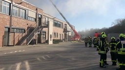 Feuerwehrleute löschen den Brand in einer Halle mit Restmüll