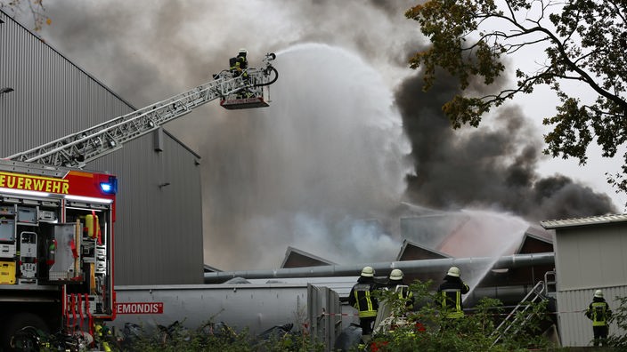 Feuerwehrleute auf einer Drehleiter versuchen den Brand an einem Bielefelder Textilwerk zu löschen