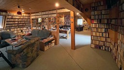 Ein großer Raum mit gefüllten Bücherregalen zu allen Seiten. 