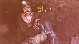 Der Bergbauingenieur und Büchersammler Bruno Schröder in einem Bergbau mit Stirnlampe und Arbeitskleidung.