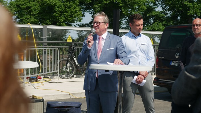 Paderborns Bürgermeister Michael Dreier (CDU) spricht zur Einweihung der neuen Brücke in ein Mikrofon. Neben ihm: Bauleiter Andrei Seibel