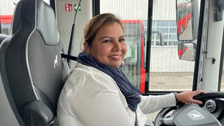 Eine Frau sitzt am Steuer eines Busses.