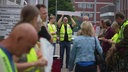 Demosnstrierende vor dem Klinikum. Der Fokus liegt auf einem Mann mit Schild