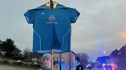 Ein Thyssenkrupp-Trikot wird bei der Demo gegen die Schließungspläne bei Thyssenkrupp hochgehalten.