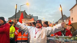 Demonstrant hält zwei Fakeln hoch. Hinter ihm sind weitere Demonstrierende zu sehen.