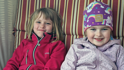 Zwei siebenjährige Mädchen lächeln in die Kamera.