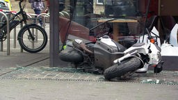 Ein Motorroller liegt zwischen Scherben auf dem Boden.
