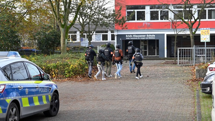 SEK-Kräfte gehen mit Westen und Waffen auf den Eingang einer Schule zu