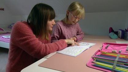 Mutter und Tochter sitzen vor den Hausaufgaben