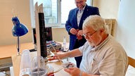 Norbert Müller (vorne) repariert ein Elektrogerät