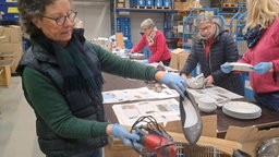 Ddrei Frauen an einem Tisch, die Spenden durchschauen.