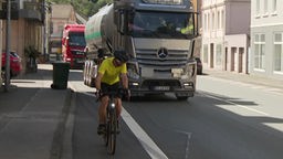 Radfahrer Christian Preuß vor einem LKW auf einer engen Straße