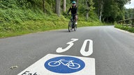 Auf dem Foto ist ein Mann auf einem Fahhrad zu sehen, der die entsprechend markierte Fahrradstraße entlang fährt