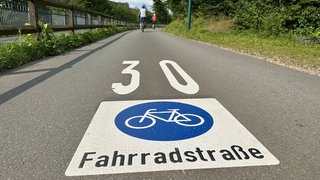 Foto von zwei Personen, die mit dem Fahrrad über die markierte Fahrradstraße fahren