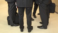 Die Beine einer Gruppe Männer in Anzügen.