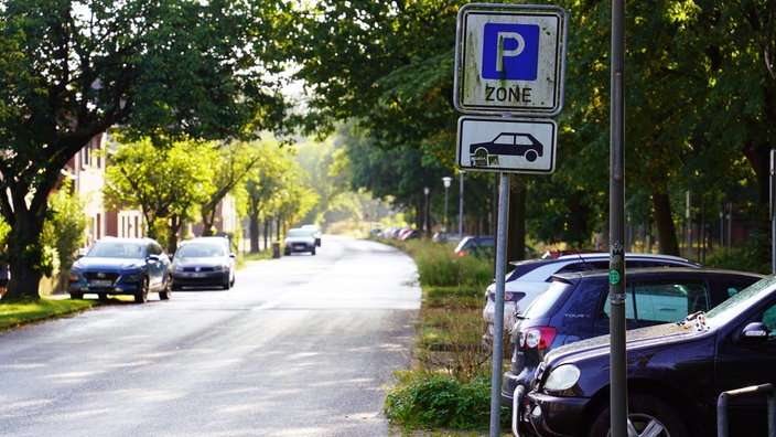 Eine Straße mit parkenden Autos am Seitenstreifen und auf einem Parkplatz