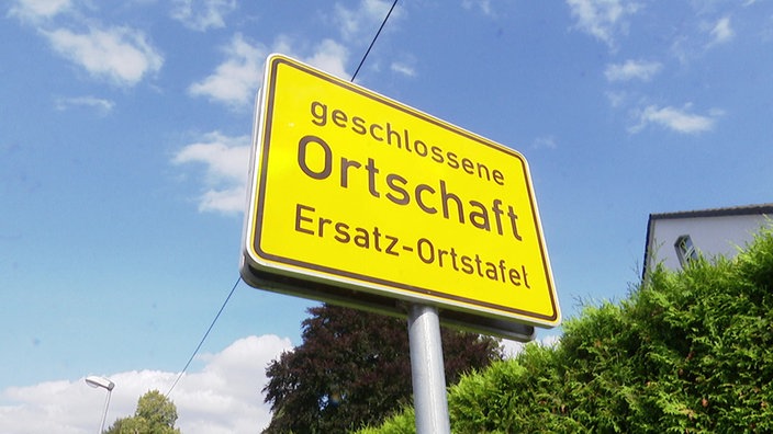 Gelbes Ortsschild mit der Aufschrift: "Geschlossene Ortschaft. Ersatz-Ortstafel."