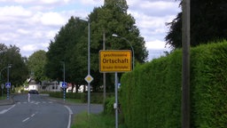 Gelbes Ortsschild mit der Aufschrift: "Geschlossene Ortschaft. Ersatz-Ortstafel."