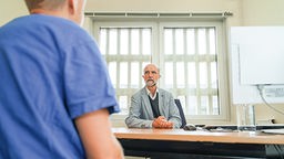 Ein Psychiater sitzt einem Gefängnisinsassen gegenüber