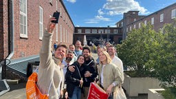 Person macht ein Selfie mit einer Gruppe vor dem Bielefelder Lenkwerk.