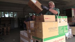 Ehrenamtliche packen Kartons mit Hilfemitteln