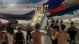 Befreite Passagiere stehen vor dem Flugzeug 