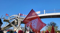 Flagge der IG-Metall, darunter Streikende 