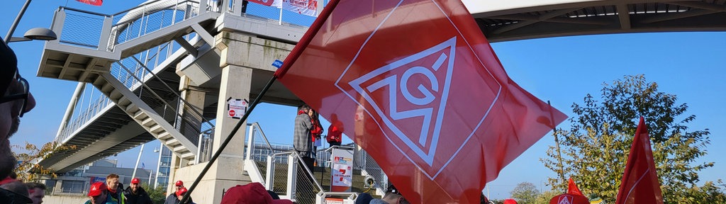 Flagge der IG-Metall, darunter Streikende 