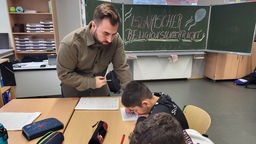 Ein Lehrer unterrichtet Jungs im Klassenraum. 