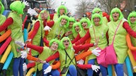 Eine Gruppe Frauen mit bunten Raupen-Kostümen und grünen Perücken posiert vor der Kamera