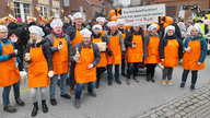 Der Sassenberger Kolping-Verein trägt orangene Schürzen und Kochmützen auf dem Kopf.