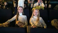 Zweri Mädchen sitzen in Kinosesseln.