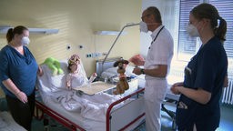 Ein Arzt der Kinderklinik ist bei einem Patienten im Zimmer mit einem Luftballon. 