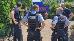 Vier Polizeibeamte in Uniform in einer Kleingartenanlage