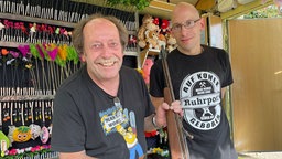 Zwei Männer, einer mit Luftgewehr, in einem Schießstand